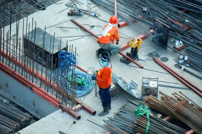 Design reference: workers placing steel reinforcing bar on a concrete deck at a commercial construction site, seen from above