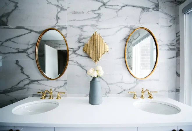 Bathroom remodeling inspiration: marble wall with a double vanity, brass fixtures and round mirrors