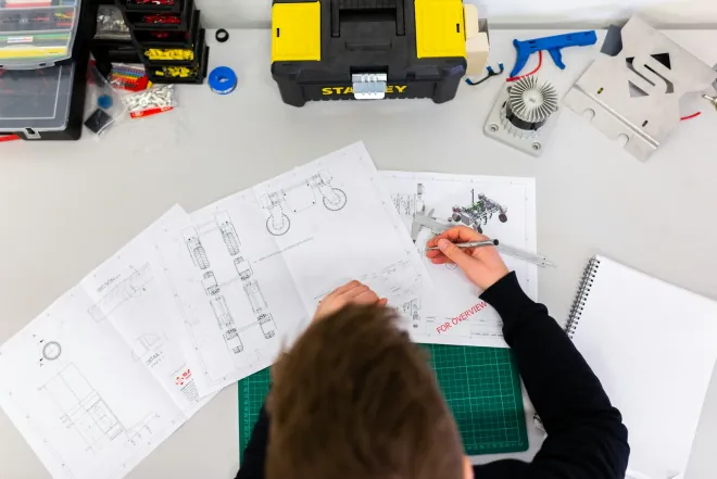 Design reference: a workbench with pencil drawings, a cutting mat and hand tools, the planning that comes before a fixed price