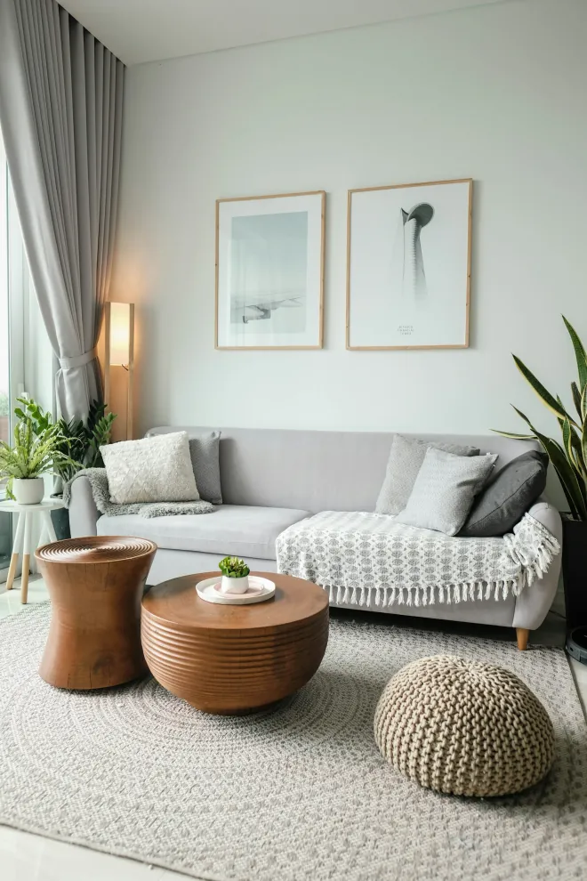 Design reference: pale living room with a low sofa, framed prints, a ribbed side table and a floor pouf on a round jute rug