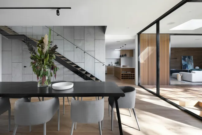 Design reference: dining area beside an open-riser stair, with a black table, a glazed wall and a slatted timber screen
